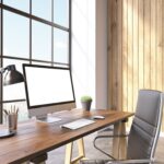 Ein Schreibtisch mit einem iMac und einem leeren Stuhl davor