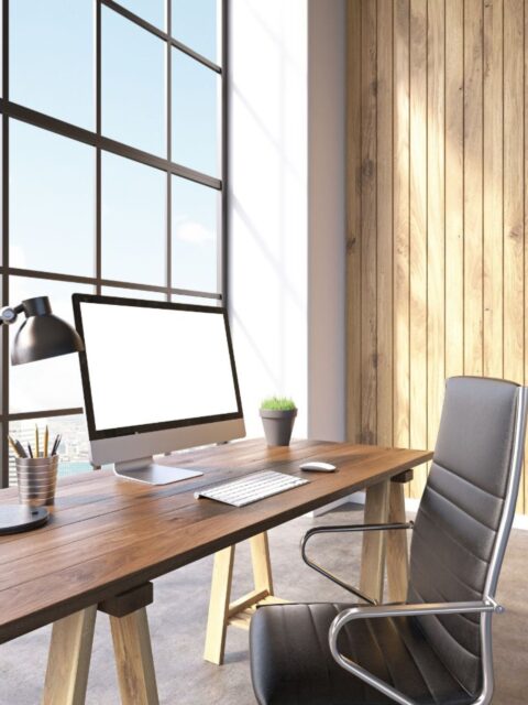 Ein Schreibtisch mit einem iMac und einem leeren Stuhl davor