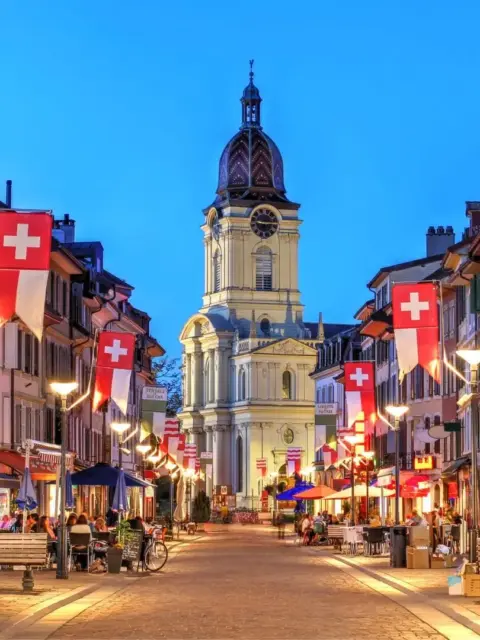 Eine Stadt am Abend als Symbol für Steuern in der Schweiz