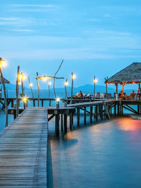 Ein beleuchteter Steg der ins Wasser in Thailand führt